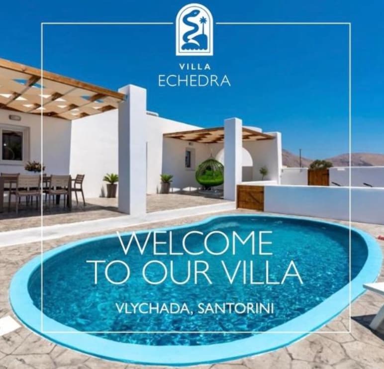 White Santorini villa with a blue oval pool, wooden pergola, and shaded outdoor dining area.