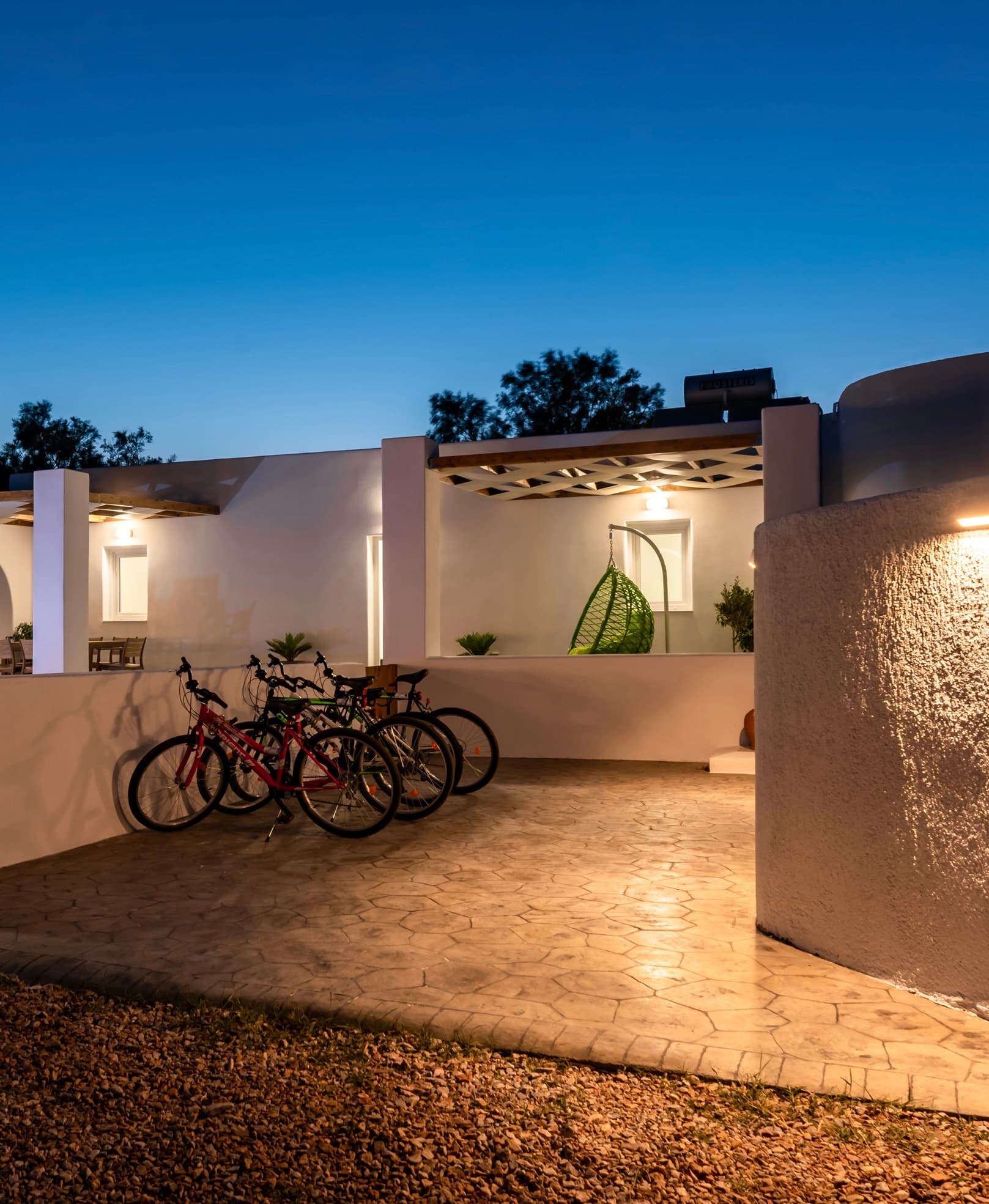 Bicycles parked on a stone patio outside a modern white villa at twilight.